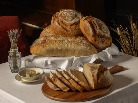 Freshly baked sourdough in a linen-lined basket, with sliced bread and butter