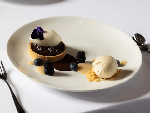 Chocolate tart with vanilla ice cream, berries and a pansy