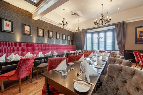 Crimson velvet banquette seating beside a table laid for dinner