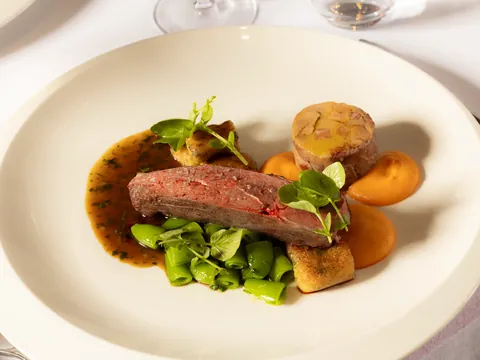 Sliced roast meat with peas, carrot purée and a golden croquette