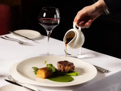 Sauce poured at the table over a beef main, with red wine