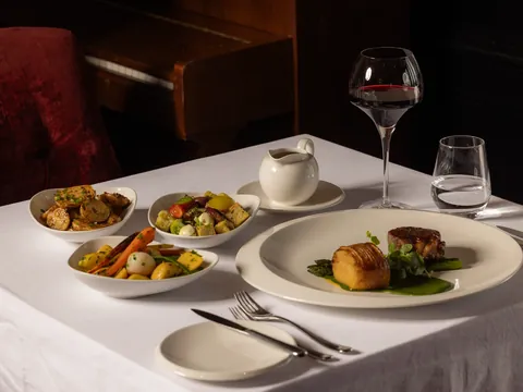 A beef main with seasonal side dishes and a glass of red wine