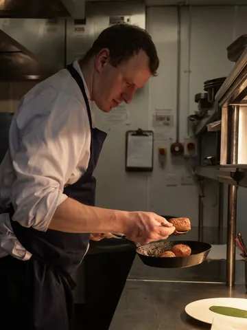 A chef plating a seared beef fillet in the Fahrenheit kitchen